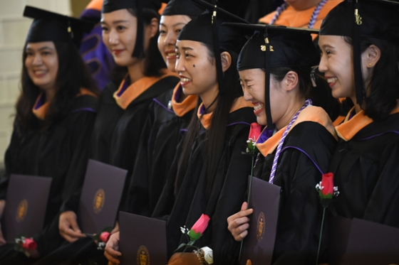 Photo of a group of international students in caps and gowns, at a Chatham University commencement ceremony