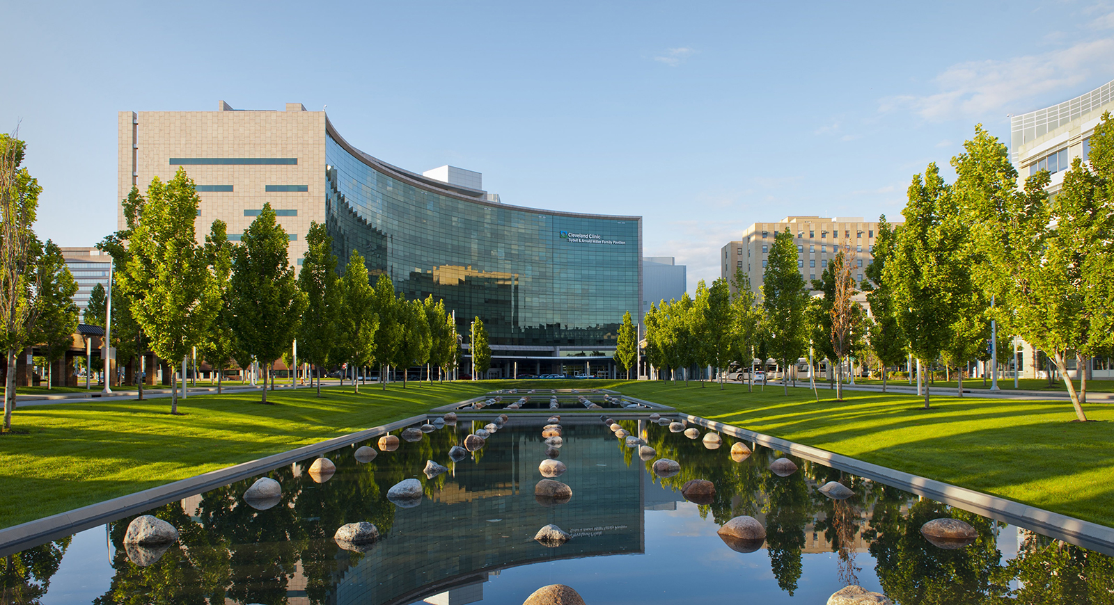 Exterior of class Cleveland Clinic building and its pond situated in a manicured green lawn.