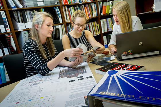 Photo of three Chatham University students working at a table in the library