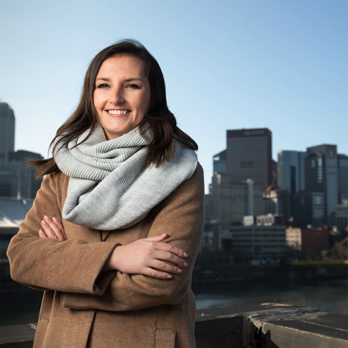 Photo of Caitlin Fadgen, smiling in front of the Pittsburgh skyline
