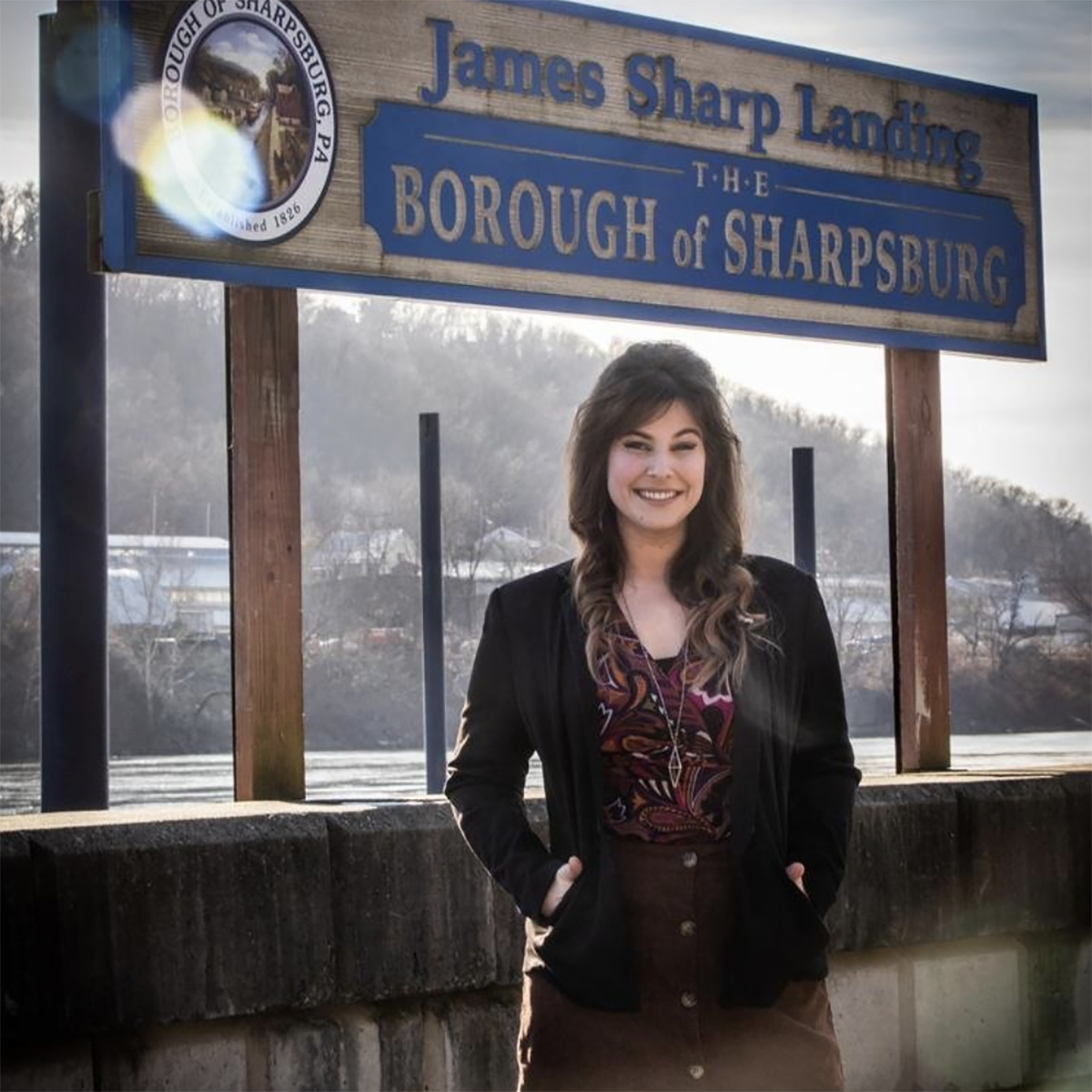 Photo of Brittany Reno, Mayor of Sharpsburg, posing in front of the town boundary sign