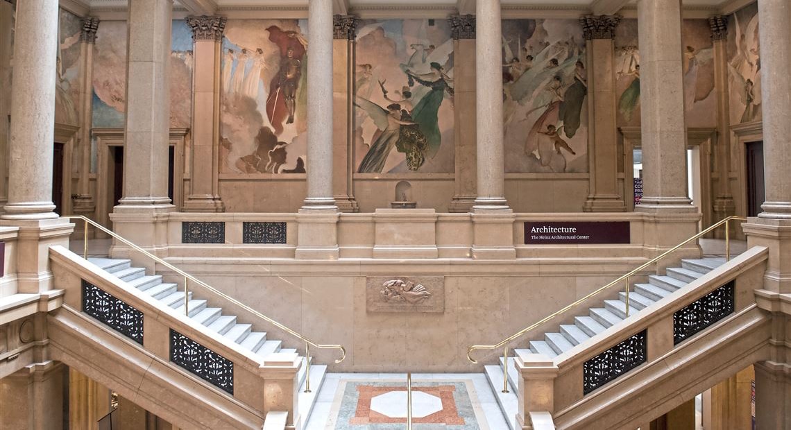 Photo of two large marble staircases descending into a lobby at the Carnegie Museum of Natural History. 