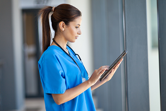 Photo of a nurse in blue scrubs looking at a chart