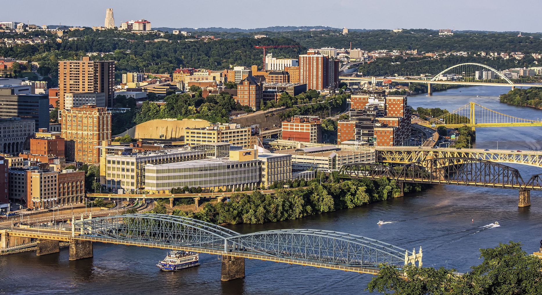 Photo of the Pittsburgh skyline with a river and yellow bridges