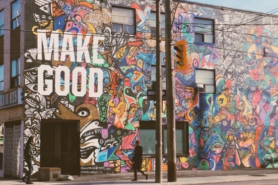 Photo of a colorful graffiti wall on the side of a brick building with the words Make Good in white.
