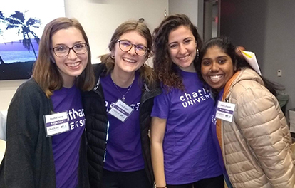 Photo of four female Chatham University students smiling and posing together in purple Chatham t-shirts.