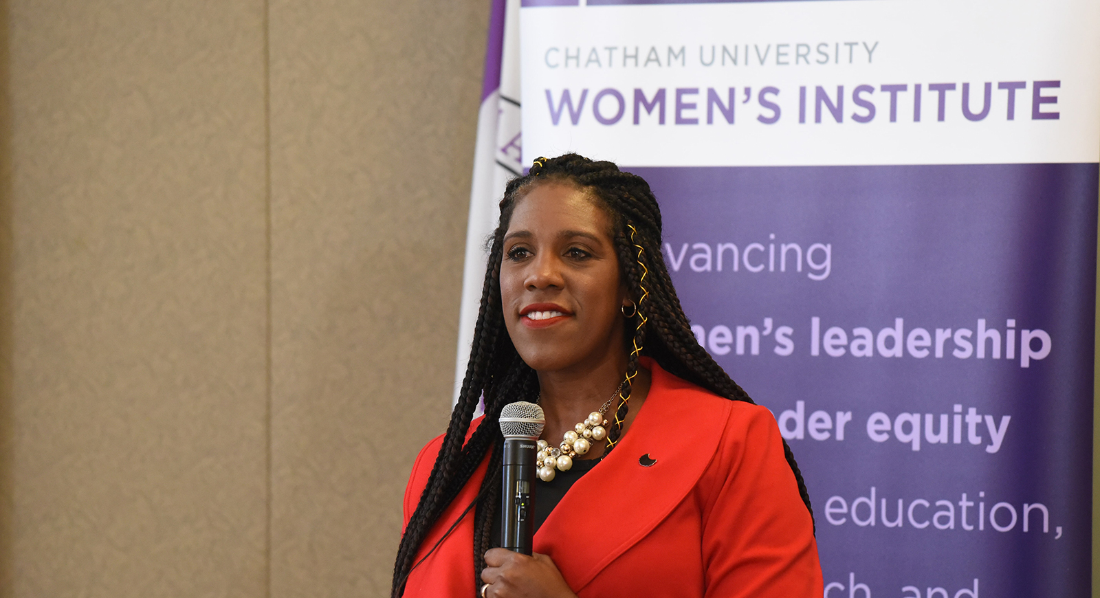 Photo of a woman presenting in front of a banner that reads Chatham University's Women's Institute