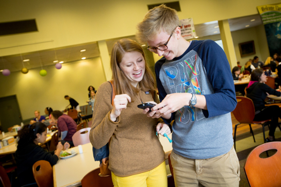 Photo of two Chatham University students smiling and looking at a phone together