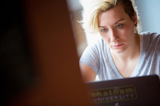 Photo of a female Chatham University student looking at a laptop
