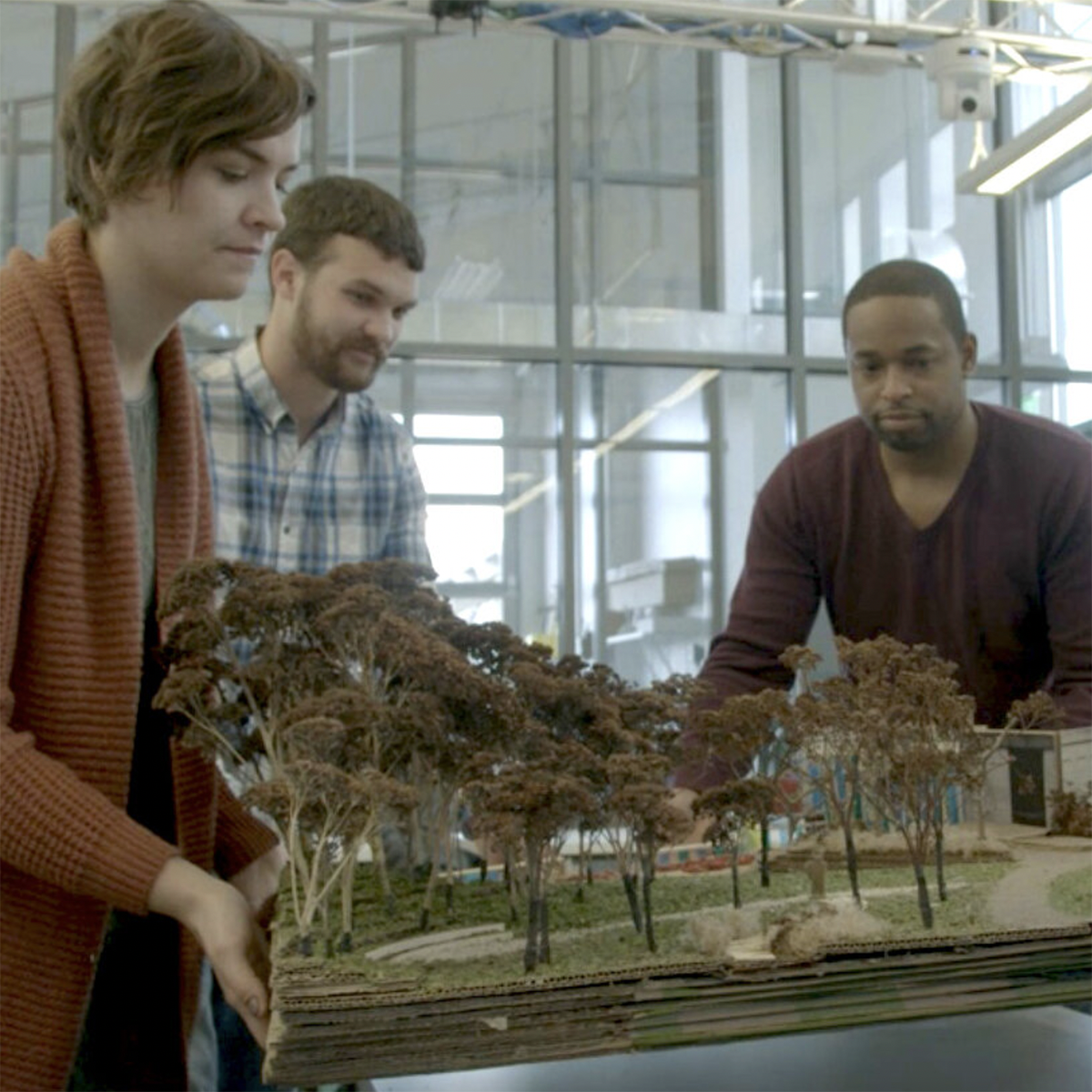 Photo of three students working together over an architectural model