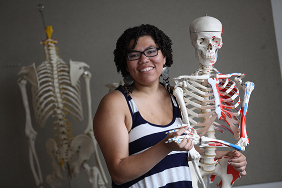 Photo of a Chatham University student posing with a skeleton model