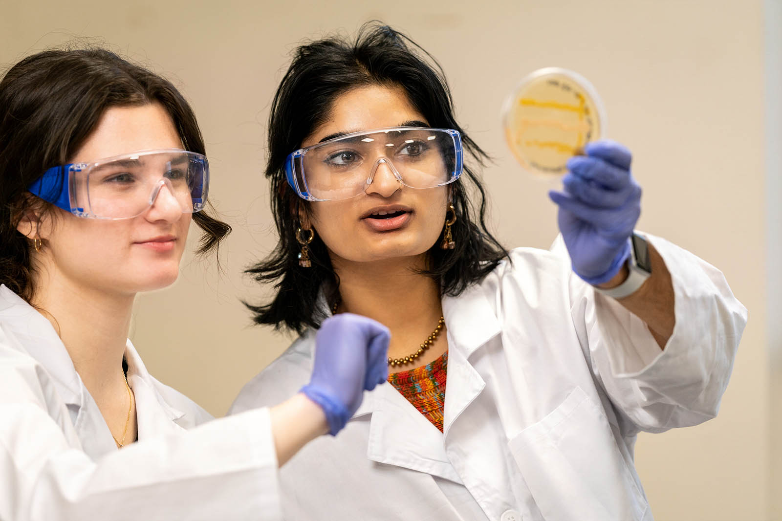 Two students in protective lab gear work on a science experiment together