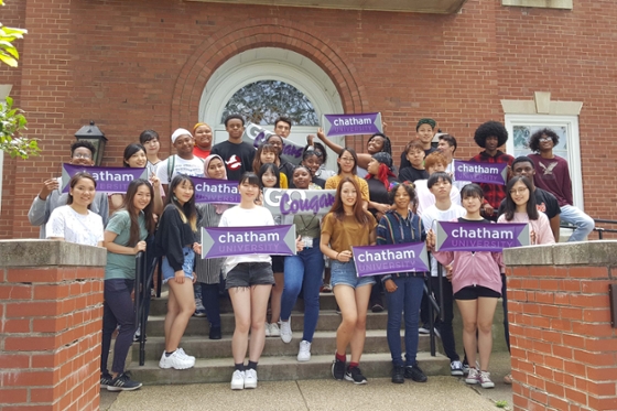 Photo of a group of international students on Chatham's campus, holding Chatham University signs.