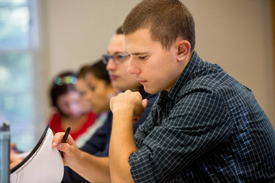 Photo of a male Chatham University paging through notes in a lecture hall