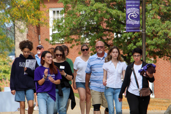 Photo of a student in a Chatham University sweatshirt, working at a laptop in a lecture hall and taking notes