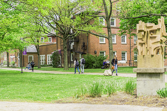 Photo of Chatham University students walking across the grassy Shadyside Campus