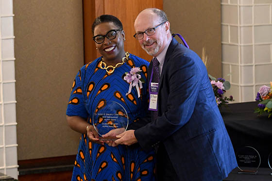Photo of President Finegold presenting a alumna with an award