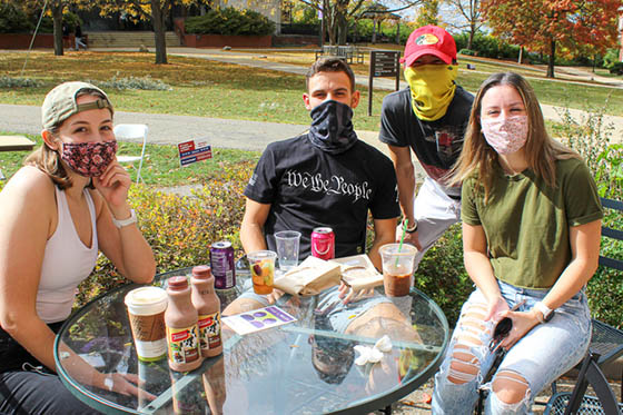 Photo of four Chatham University students in masks, hanging out together outside on Shadyside Campus