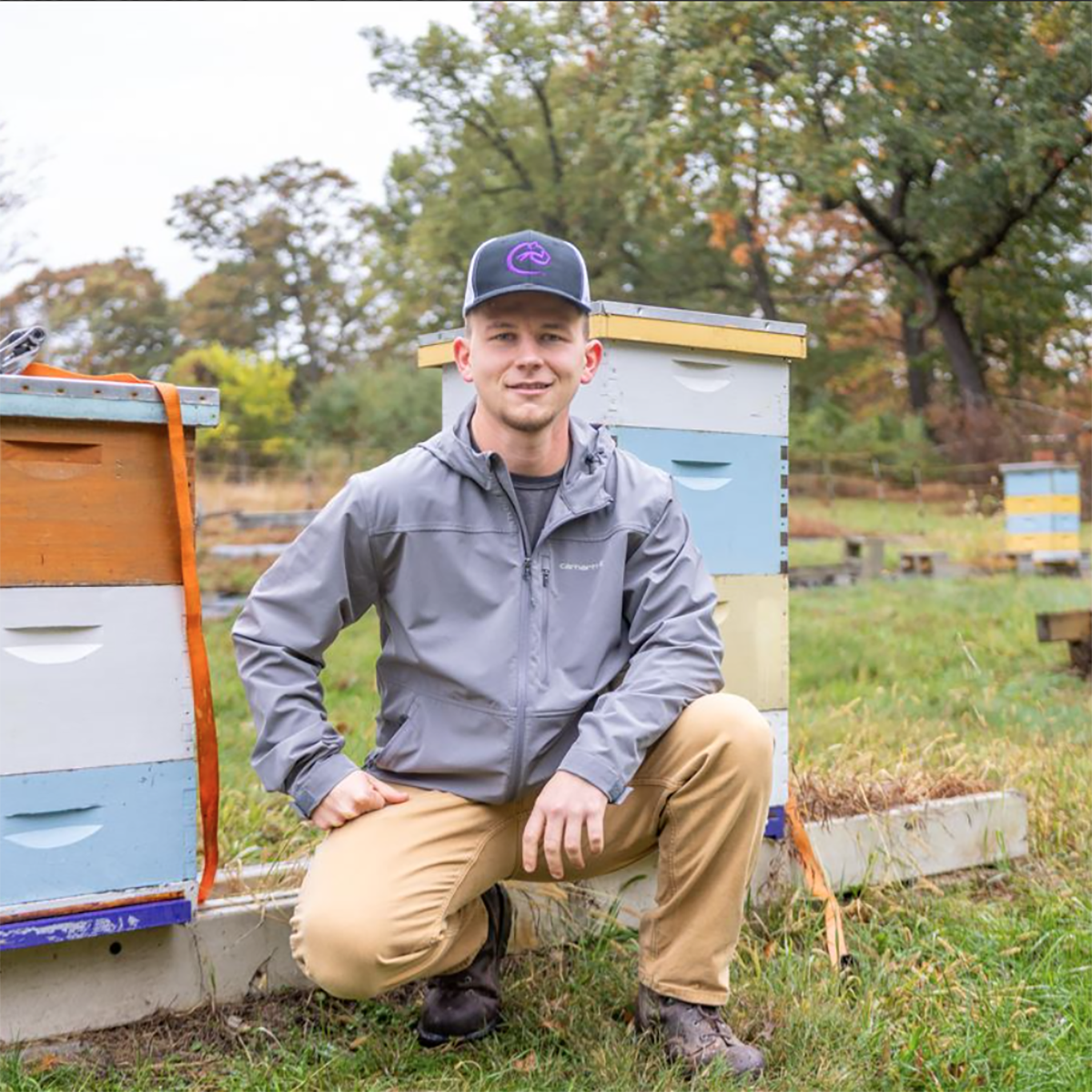 Chatham Sustainability student, Anthony Ondo, in front of beehives (Pittsburgh Post-Gazette)