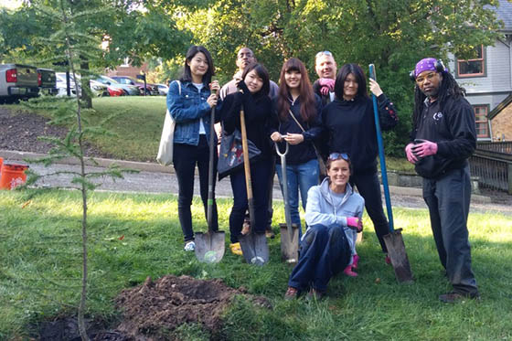 Photo of a group of Chatham University students and staff members posing around a tree they planted