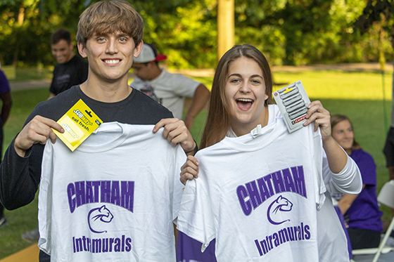 Photo of two Chatham University students holding up their intramural sports t-shirts and smiling