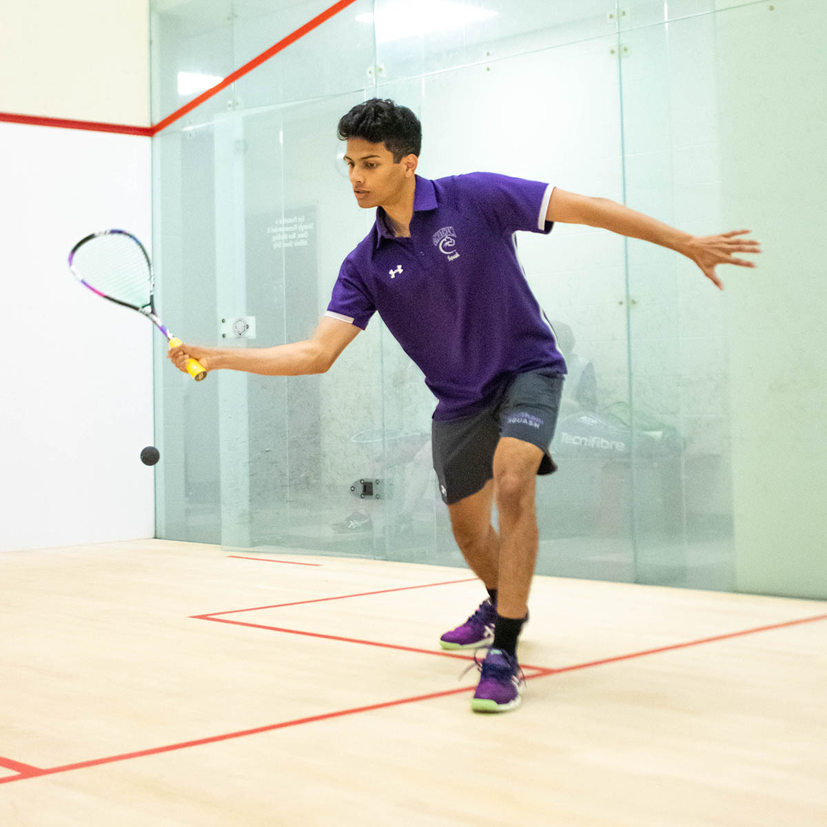 Photo of Jared playing squash in a purple Chatham uniform