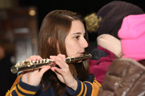 Photo of a student in a band uniform playing the flute outside