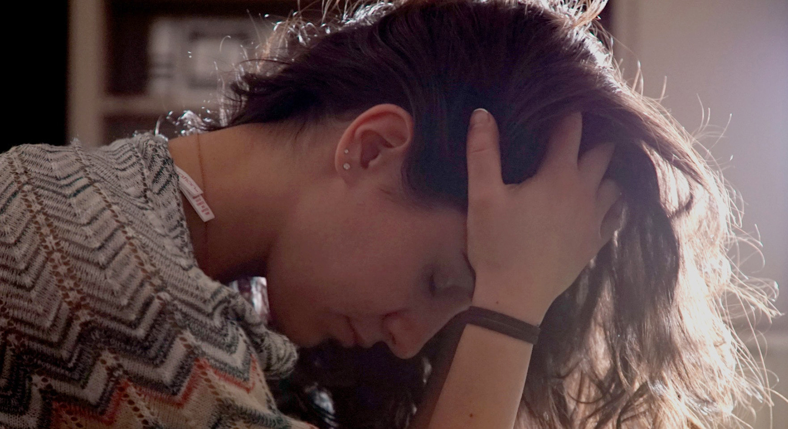 Photo of a woman leaning over with her head in hands and eyes closed.